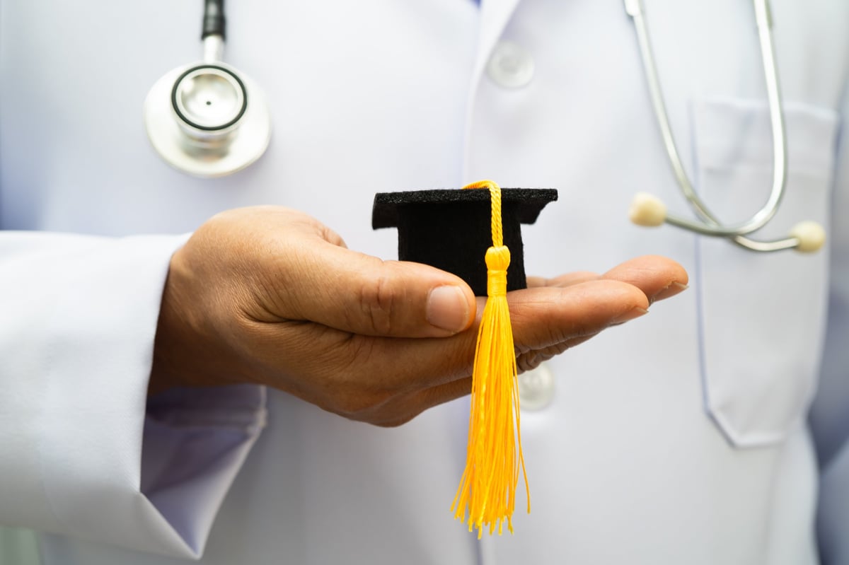 Asian woman doctor holding a graduation hat in hospital, representing medical education