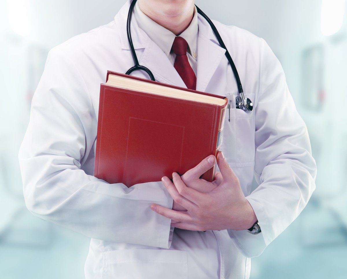 Doctor with a stethoscope and a book in a hospital corridor